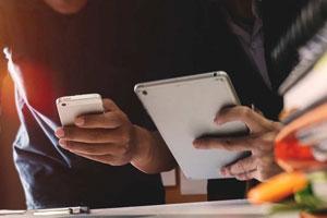 A person uses a smartphone while another person uses a tablet.